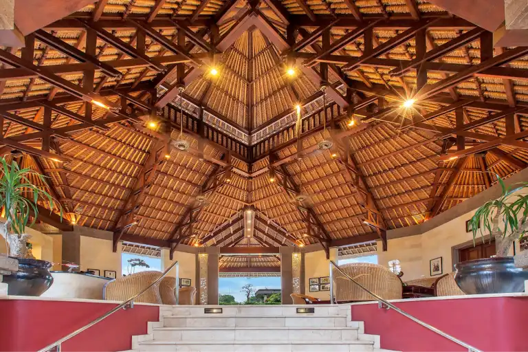 Open‑air Bali resort lobby with thatched roof, wooden beams, and tropical décor