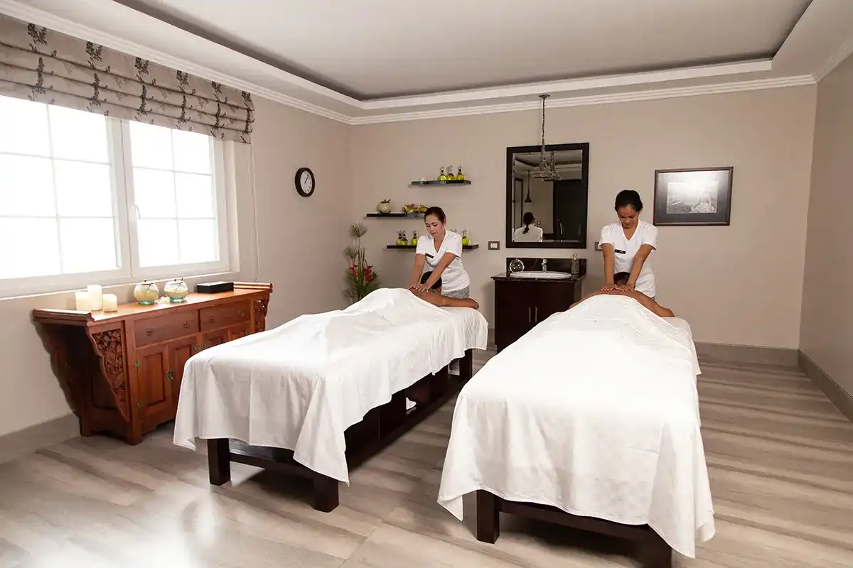 Massage therapists giving treatments in Bali spa room with wooden décor and calming ambiance