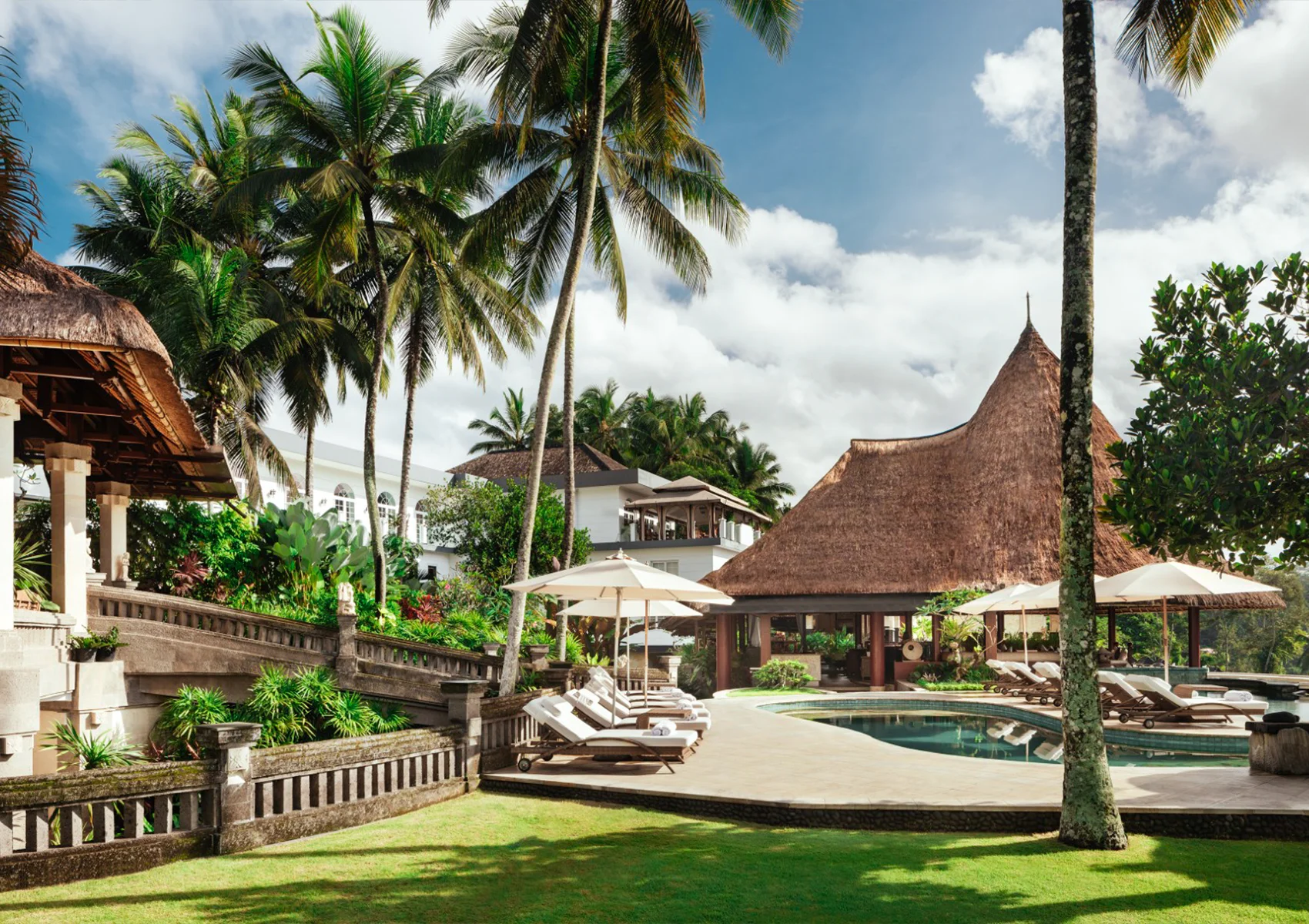 Luxury tropical garden and main pool area at Viceroy Bali in Ubud featuring elegant Balinese architecture, palm trees, sun loungers, and a secluded honeymoon resort atmosphere in the Valley of the Kings
