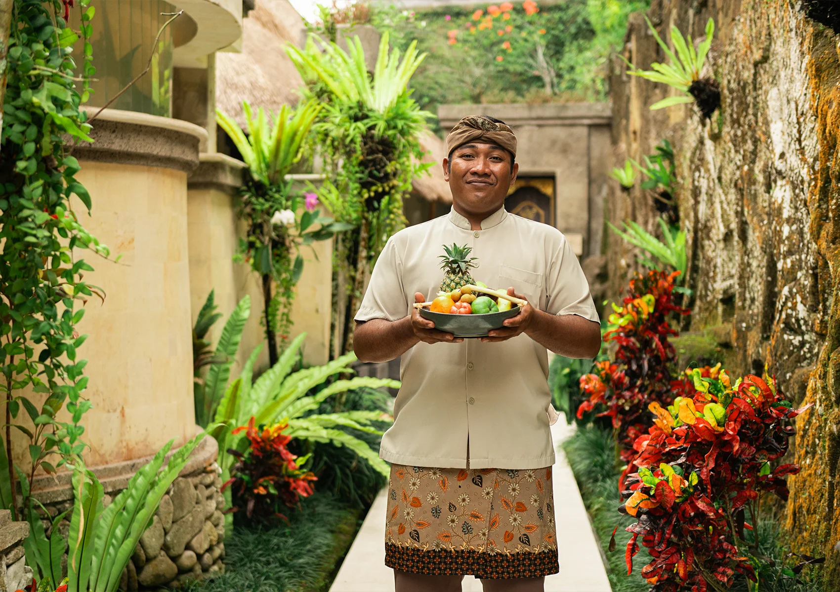 Warm Balinese hospitality at Viceroy Bali with a resort staff member welcoming guests through a lush tropical pathway in the secluded luxury resort setting of Ubud’s Valley of the Kings
