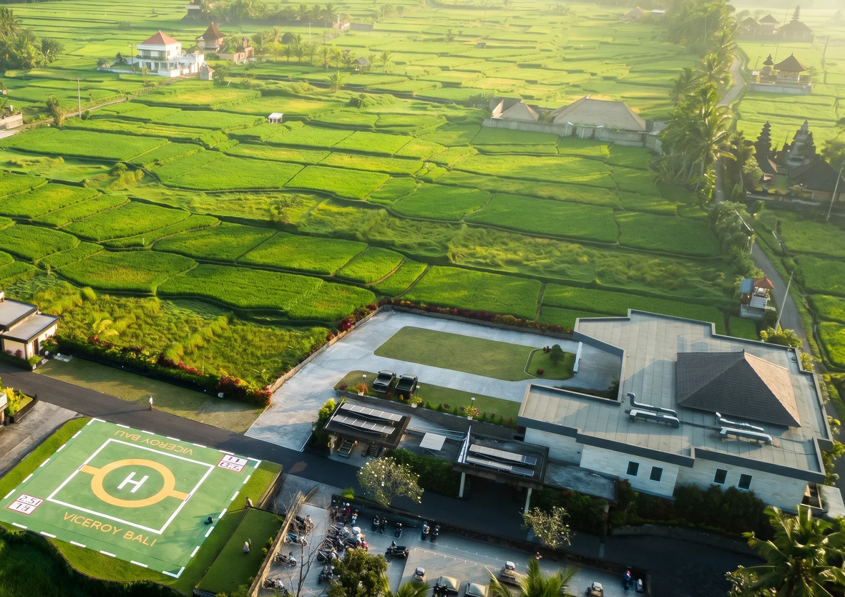 Aerial view of lush green rice fields surrounding Viceroy Bali in Ubud with tropical landscapes and countryside scenery at sunrise.